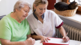 caregiver assisting her patient in writing